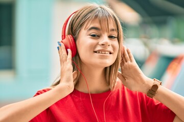 Caucasian teenager girl smiling happy using headphones at the city.