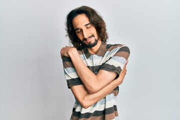 Young hispanic man wearing casual clothes hugging oneself happy and positive, smiling confident. self love and self care