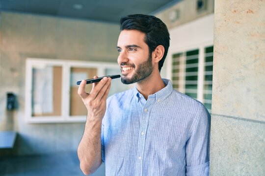 Young hispanic man smiling happy sending audio message using smartphone at city.