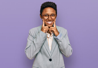 Young african american woman wearing business clothes smiling with open mouth, fingers pointing and forcing cheerful smile