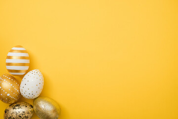 Easter golden decorated eggs on yellow background. Minimal easter concept. Happy Easter card with copy space for text. Top view, flatlay