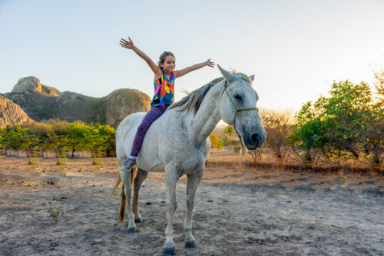 Crian&ccedil;a feliz montada em p&ecirc;lo de cavalo branco