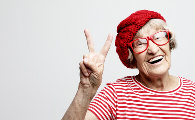 Old woman laugh and showing peace or victory signat camera. Emotion and feelings. Portrait of...