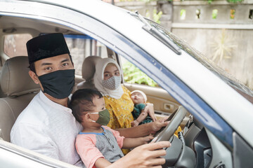 Muslim family wearing face mask during travel by car on eid mubarak celebration. asian people going back to their hometown