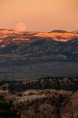 Naklejka premium dramatic sunset with the harvest full moon in view in Bryce Canyon National Park in Utah