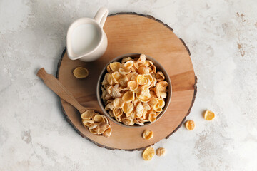 Bowl with tasty cornflakes on light background