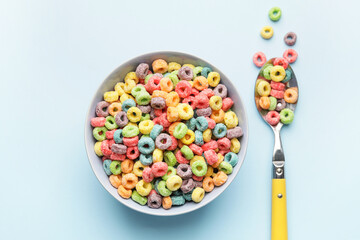 Bowl and spoon with tasty cereal rings on color background