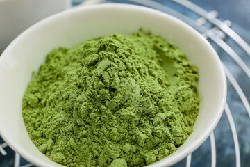 Bowl with powdered matcha tea on color background, closeup