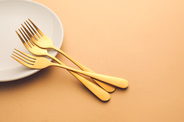 Stylish forks and plate on color background