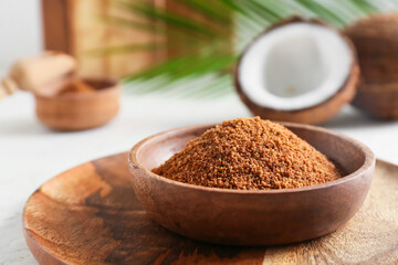 Bowl of sugar and sweet coconuts on light background