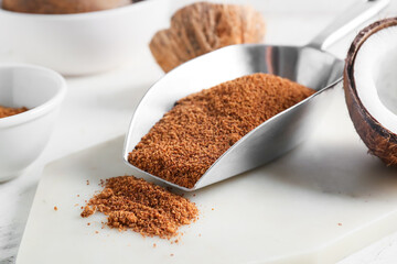 Scoop of sweet coconut sugar on light background