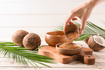 female hand and sweet coconut sugar on light wooden background