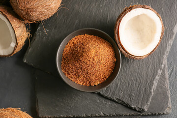 Sweet coconuts and bowl of sugar on dark background