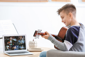 Little boy taking music lessons online at home
