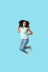 Fototapeta na wymiar Jumping young woman against color background