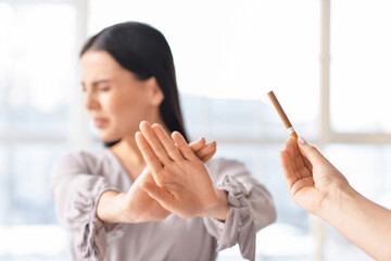 Young woman rejecting cigarette at home. Concept of refusing from bad habit