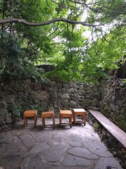 Old stone wall in front of wooden purple color chair stools stands crafted a great concept background.