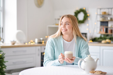 Beautiful young woman drinking hot chocolate at home on Christmas eve