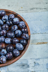 Garden plums in a plate on a blue background