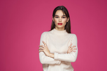 Obraz premium Brunette with long hair red lips cosmetics white sweater pink background cropped view