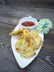 Anchovies fritters or locally known as cucur bilis with chilli sauce dip. Selective focus points. Blurred background