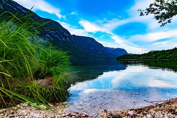 Bohnij Lake beach with Julian Alpes panorama - Bohnijsko Jezero, Slovenia, beautiful mirror water in late afternoon