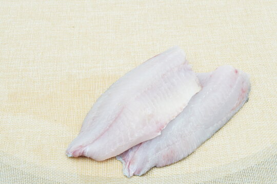 Raw fresh tilapia fillets with seasonings ready to be cooked,