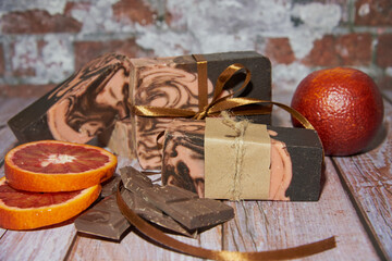 Natural handmade soap with chocolate and orange on a wooden countertop.