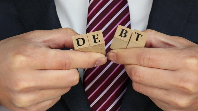 借金と書かれた木のブロックを半分に割る