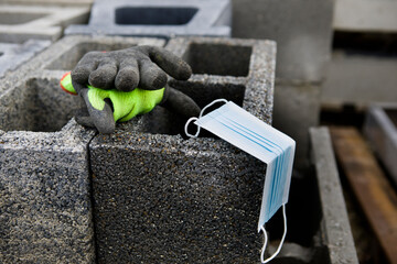 Coronavirus COVID-19 protective mask placed on concrete slag blocks with gloves