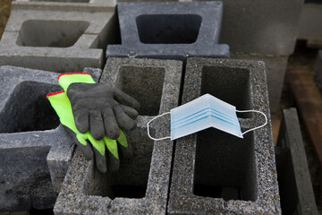 Coronavirus COVID-19 protective mask placed on concrete slag blocks with gloves