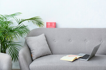 Interior of room with calendar, laptop and notebook on sofa