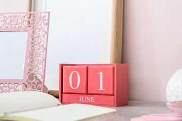 Cube calendar with date JUNE 1, notebook and decor on table in room
