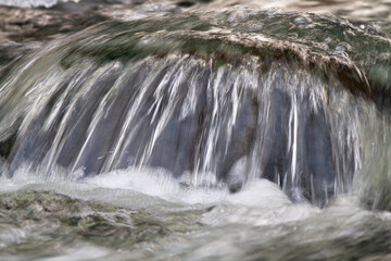 water flows over a boulder in the river