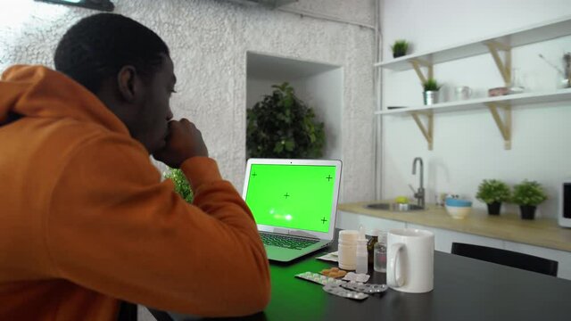 Back view of sick young african american man types on the notebook with green screen