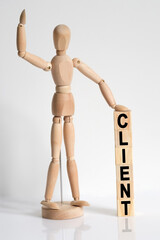 The wooden man raised his hand, and under his left hand he has cubes with the inscription - CLIENT