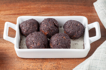 sweet brown cake balls baked in the oven are dipped in to stump or syrup and covered with poppy seeds. This dessert is called Hashasli tatli (traditional Turkish recipe)