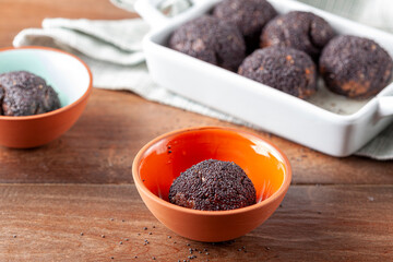 sweet brown cake balls baked in the oven are dipped in to stump or syrup and covered with poppy seeds. This dessert is called Hashasli tatli (traditional Turkish recipe) selective focus close up image