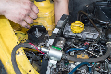A mechanic installs a timing belt on a yellow diesel car