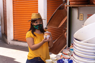 Muchacha con cubrebocas en mercado de artesanías. Artesanías mexicanas.