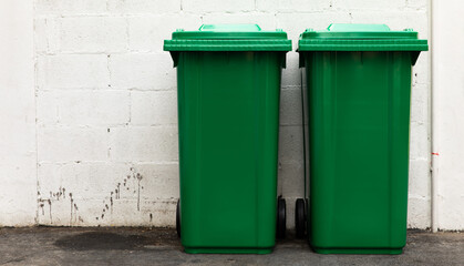 A new unbox green large bins ready to use on footpath and white concrete wall