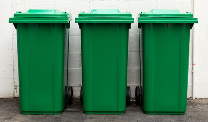 A new unbox green large bins ready to use on footpath and white concrete wall