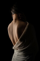 Back view of a beautiful half naked woman. Vertical shot, isolated black background.