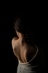 Back view of a beautiful half naked woman. Vertical shot, isolated black background.