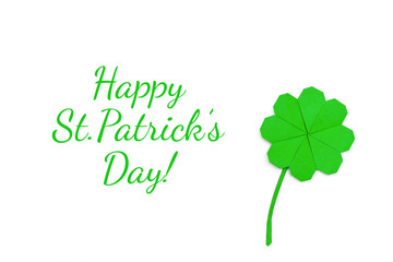 A leaf of clover, folded in the origami technique of green paper on a white background.Concept of St.Patrick's Day.Lettering HAPPY ST.PATRICK'S DAY!Top view, flat lay.