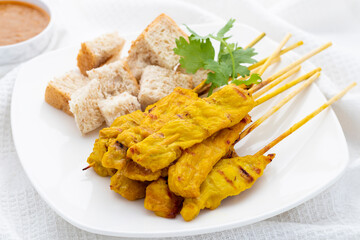 Pork satay or moo satay in Thai served with peanut satay sauce and whole wheat bread. It presents...