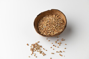 green buckwheat groats in a coconut shell on a white background top-side view