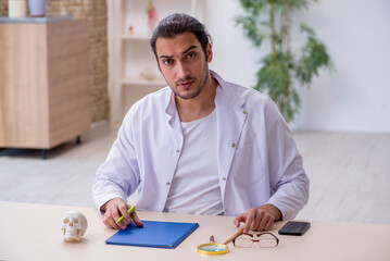 Young male doctor demonstrating human skeleton