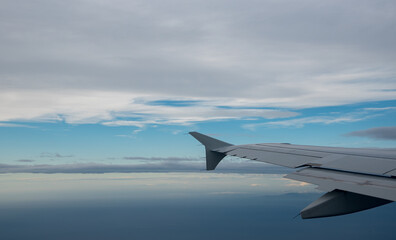 Plane wing in a flight and dramatic cloudscape white clouds over europe