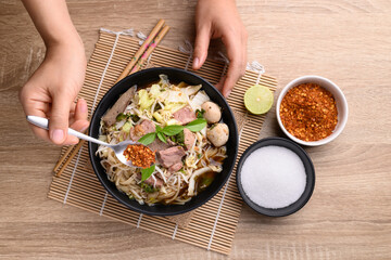 Rice noodle soup with pork, pork ball and vegetables in a bowl eating with chili, Thai noodles soup